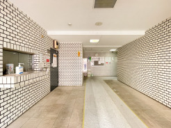 白タイル張りが印象的な共用ロビー。見通しの良い直線的な動線で、明るく清潔感のある空間です。管理人窓口もあり、日々の管理体制がしっかりしている点も安心材料のひとつです。